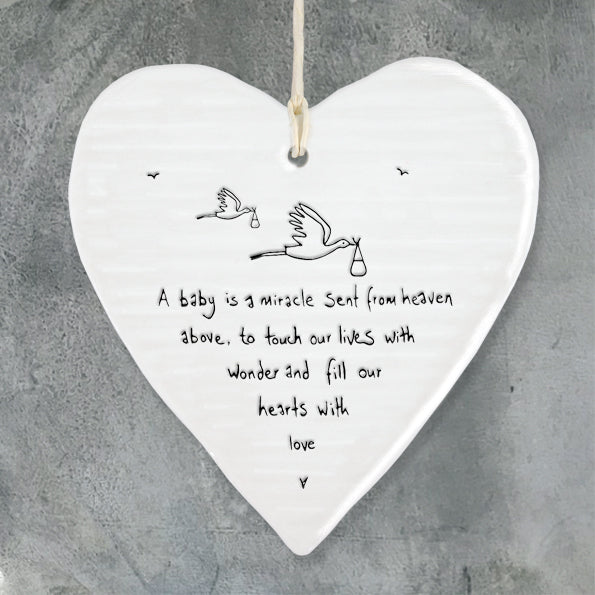 Heart-shaped ceramic plaque with a message and illustrations on a gray background